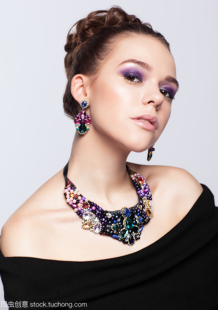 珠寶首飾在灰色的背景上的棕色頭發年輕女子